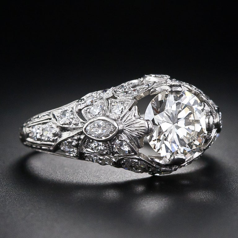 Scintillating marquise diamonds on all four sides combined with round-cut diamond ribbons and bows support this beautiful and sparkling 1.35 carat transitional European-cut diamond in this ravishing and distinctly feminine, original antique