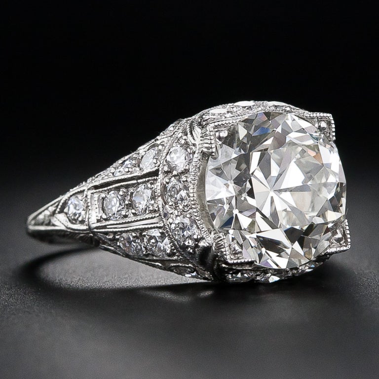 This 4.03 carat headlight always has it brights on in this stunning, striking and highly-impressive original Art Deco ring, circa 1925. The lightly tinted diamond is magnificently presented in an extravagantly ornamented platinum and diamond