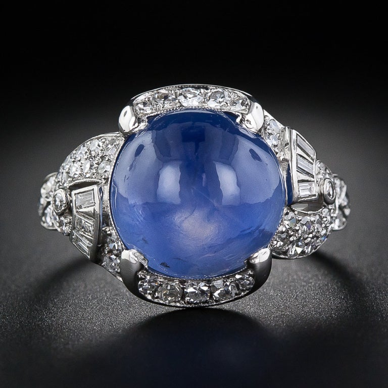 A serene and soothing cornflower blue cabochon sapphire, weighing over 15.00 carats, and exhibiting moderate asterism, glows from within a consummate platinum and diamond Art Deco ring, superbly handcrafted in platinum and diamonds, circa 1930. A
