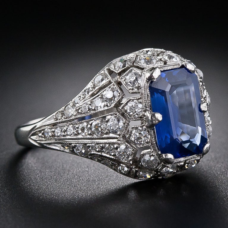An elegant, elongated emerald-cut Ceylon sapphire radiates from atop a magnificently ornamented platinum and diamond mounting in this rare and wonderful original Art Deco jewel, circa 1925. The beautiful 2.50 carat sapphire glistens from within a