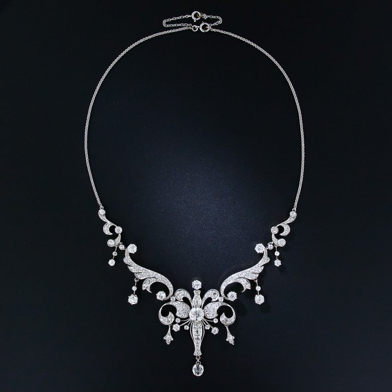 A rare, regal and wonderful antique diamond necklace, dating from the turn-of-the-twentieth century, is superbly handcrafted in platinum over gold. This majestic jewel centers on a bright and sparkling 1.75 carat European-cut diamond radiating from