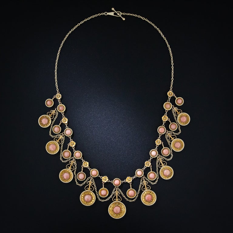 A truly exquisite and exemplary, all original Victorian - Etruscan Revival necklace shimmering with twenty-two pastel pink coral cabochons, each of which is displayed in intricately ornamented circular frames imbued with delicate granulation work