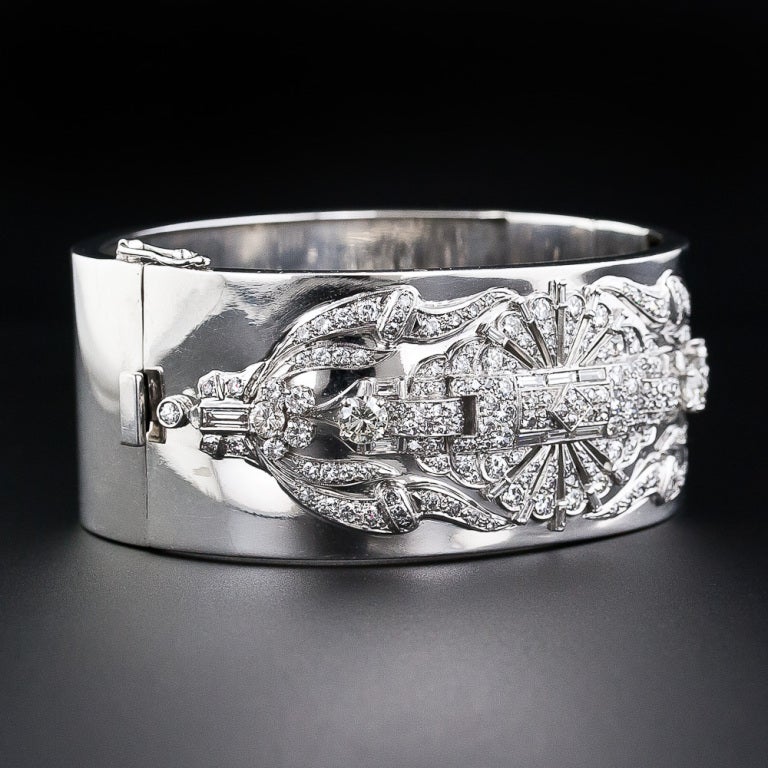 A bright and shining 1 and 1/8 inch-wide white gold hinged cuff is overlaid with a sparkling platinum and diamond Art Deco elements, formerly the centerpiece of a bracelet or brooch, to create this unique, extravagant and glamorous cuff bracelet. A