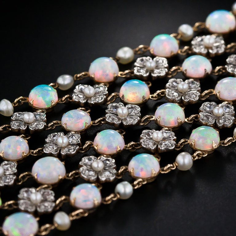 This truly magnificent and majestic treasure, dating from the turn-of-the-century - circa 1900, perfectly reflects Gilded Age opulence and Edwardian-era femininity. Vertical rows of four luminous, multi-chromatic, pastel-hued opals alternate with