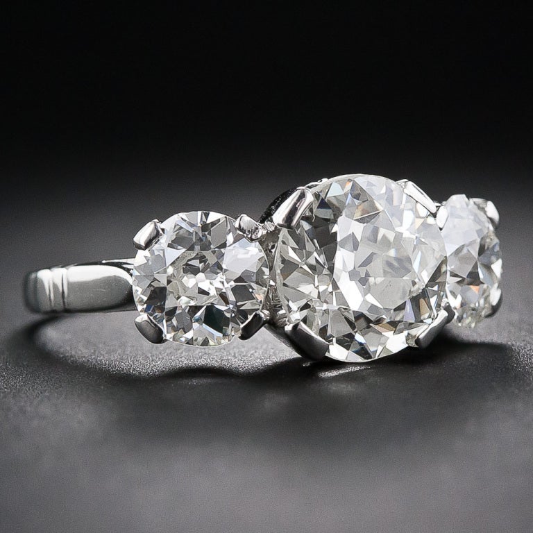 This vintage 1930s three-stone diamond ring in platinum is an original Art Deco sizzler. The 2.65 carat European-cut diamond center stone joins forces with a beautifully matched pair of European-cut side diamonds, together weighing 1.70 carats, to