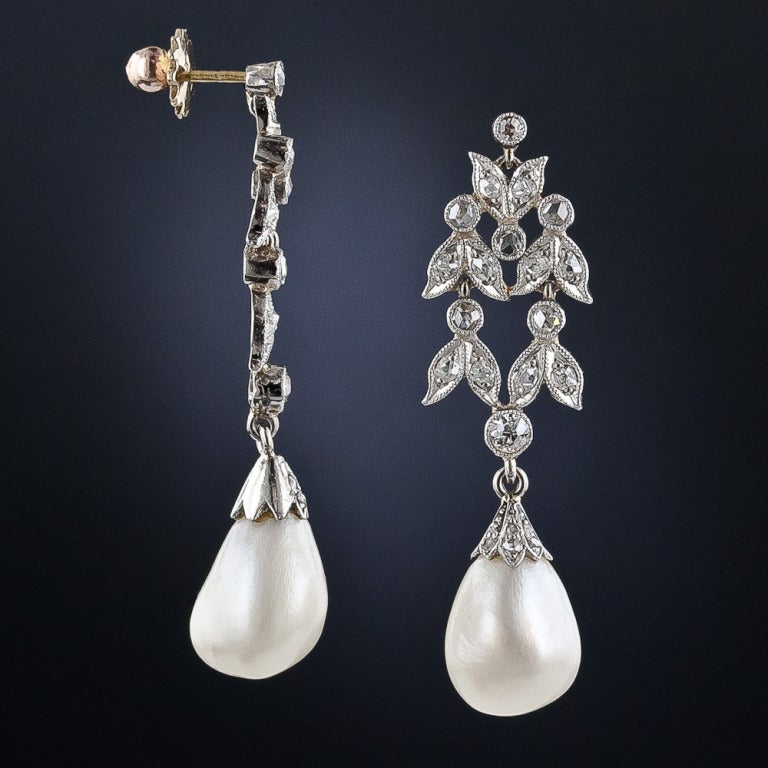 A shimmering pair of natural saltwater, or 'oriental' pearls - accompanied by a gemological certificate from the GIA - dance below delicate diamond set, foliate motif tops in these utterly delightful, refined and rarified antique drop earrings -