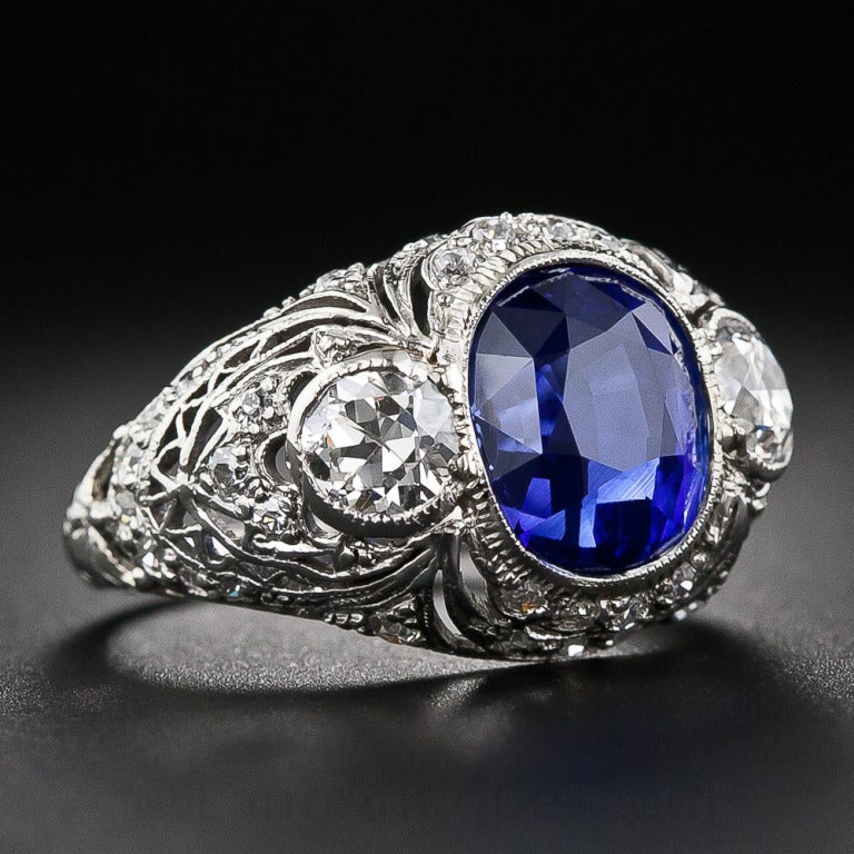 This fabulous sapphire and diamond ring, dating back to the early-20th century, displays both Edwardian and Art Deco design characteristics - geometric symmetry combined with feminine laciness. The star of the show, however, is a sumptuous rich blue