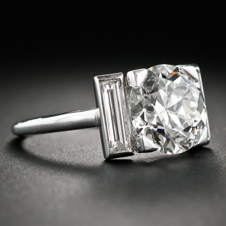 A rare and ravishing jewel from Cartier-Paris, circa 1930s. A gorgeous, bright-white European-cut diamond, weighing 3.28 carats, sizzles between a pair of long and slender straight baguette diamonds (.50 carats total) set in platinum. The diamond is