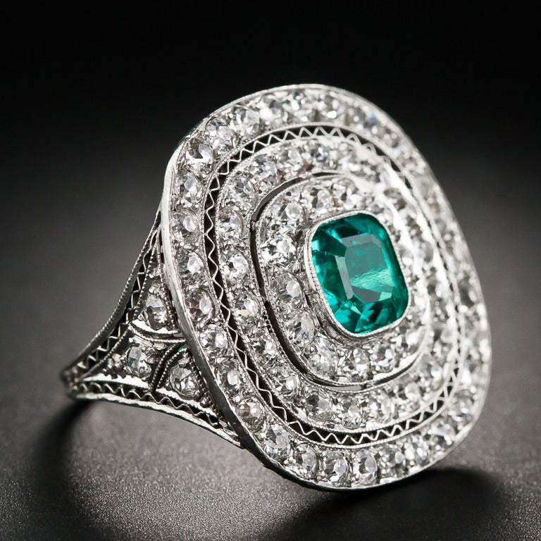 An ultra gemmy (if there is a finer specimen extant, we'd like to see it) cushion-cut emerald, weighing 1.25 carats, glistens and glows from the center of this truly spectacular, super-sized (just over 7/8 inch across) Edwardian ring, masterfully
