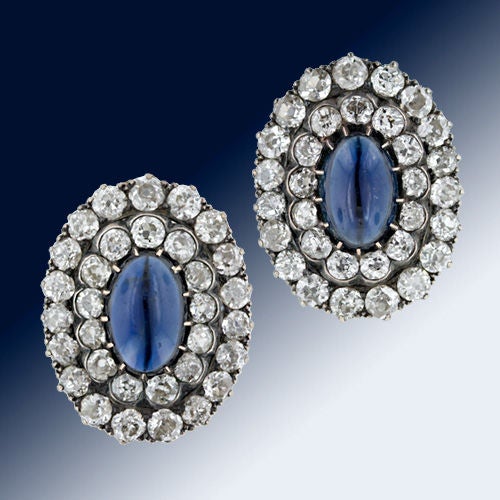 From the late 19th century, these enchanting one inch long sapphire and diamond earclips glisten with concentric ovals of white diamond sparklers totaling 5 carats. The elongated oval cabochon centers are a deep rich indigo blue. In silver over rose