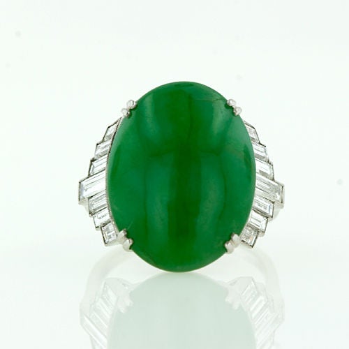 An impressive, thick oval cabochon, natural Jadeite set into a fine handmade platinum setting with a graduated fan of straight baguette diamonds. The certified natural color Jade is a deep rich kelly green with even color distribution.<br />
<br