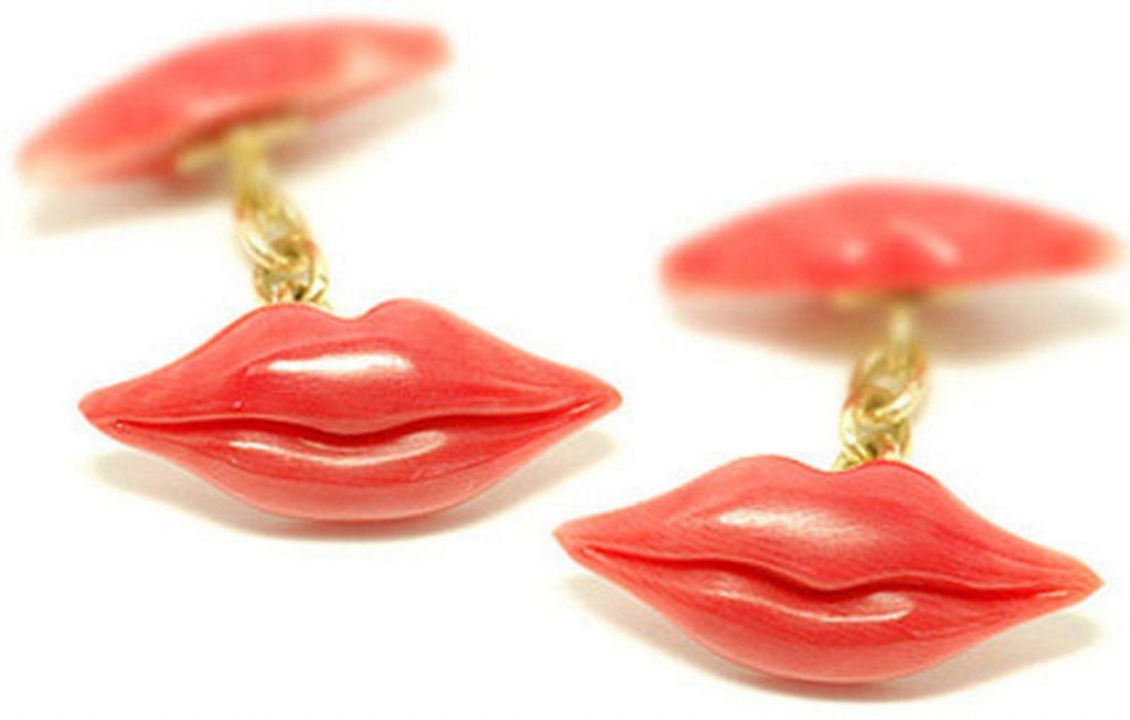 A pair of carved coral lip motif cufflinks in 18ct yellow gold chain link connections.