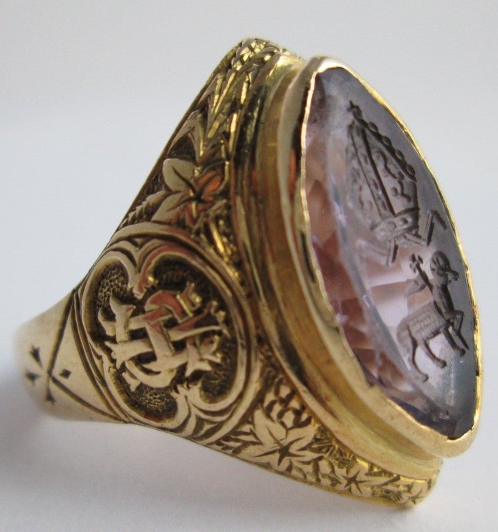 The large marquise-cut amethyst with intaglio carved the seal of the english bishop ,collet set within a heavy 18ct yellow gold mounted, scroll engraved throughout,

with the monogram and greek word christ detail to the shoulders,


hallmarked
