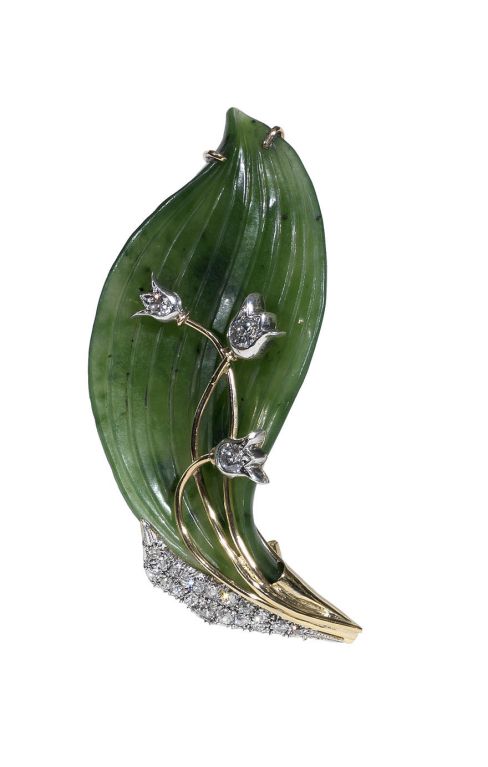 The translucent carved nephrite leaf mounted with three gold stems set with old cut european diamonds weighing approx. 2ct simulating buds, issuing from a diamond-set petal, the reverse mounted with a gold pin,
(7,5cm.) long