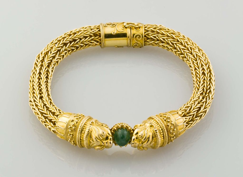 Rare and unusual 18K gold mesh bracelet by Van Cleef & Arpels. The bracelet is fashioned after the Etruscan revival style. It features a mesh chain linked body, with two lion heads coming together on a cabochon emerald of approx. 2.0cts. In very