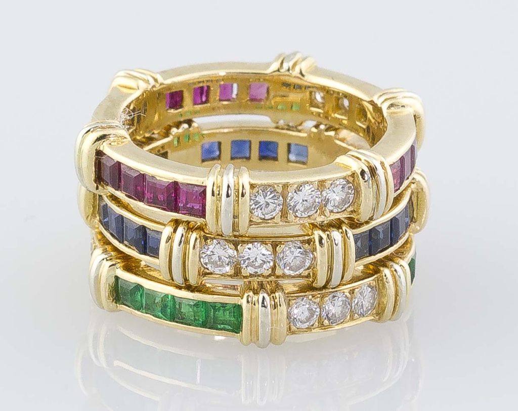 Chic and vibrant 3 band ring set by Cartier, circa 1980s.  This interesting set features 3 18k yellow gold bands with white gold accent; furthermore, each band is set with round brilliant cut diamonds alternating with either emerald, ruby, or