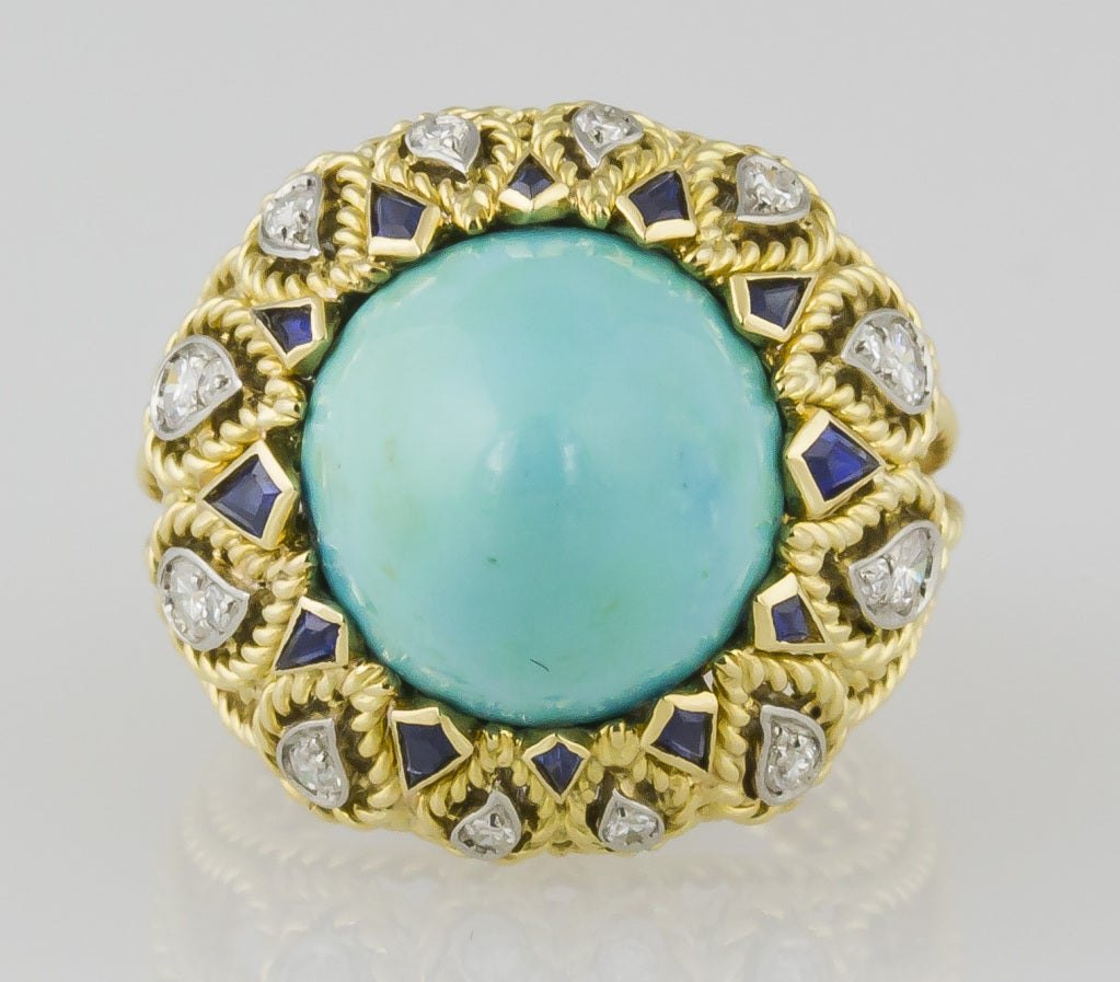 Charming and intricate 18K yellow gold, diamond, sapphire and turquoise cocktail ring by Sterle, circa 1950s. It features a twisted rope design with an approx. 12mm diameter richly colored sugarloaf cabochon turquoise, along with high grade rich