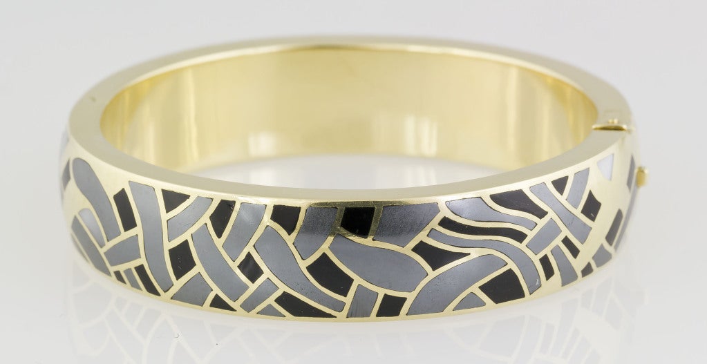 Very collectible and sought after 18K yellow gold reversible inlaid bangle bracelet by Tiffany & Co., designed by Angela Cummings. It features mother of pearl, hematite and black jade all inlaid within the 18K gold frame. Reversible with different