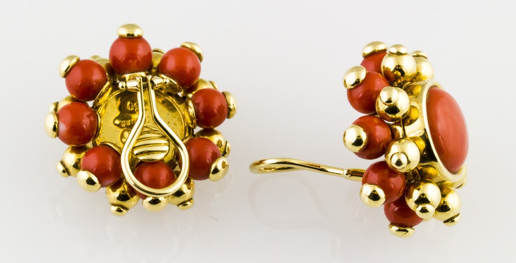 Impressive 18K yellow gold and coral ear clips by Verdura, circa 1980s. They center around a large bezel-set button shaped coral bead, surrounded 18K gold and coral beads. Coral is natural, untreated, and of exceptional color.
