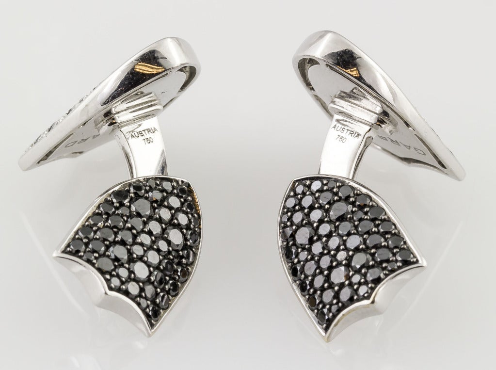 Handsome and unusual 18K white gold cufflinks set with black and white diamonds, in the likeness of shields, by Garrard.   Featuring approx. 4.0 carats of diamonds. 
Hallmarks: Garrard, Austria, 750.