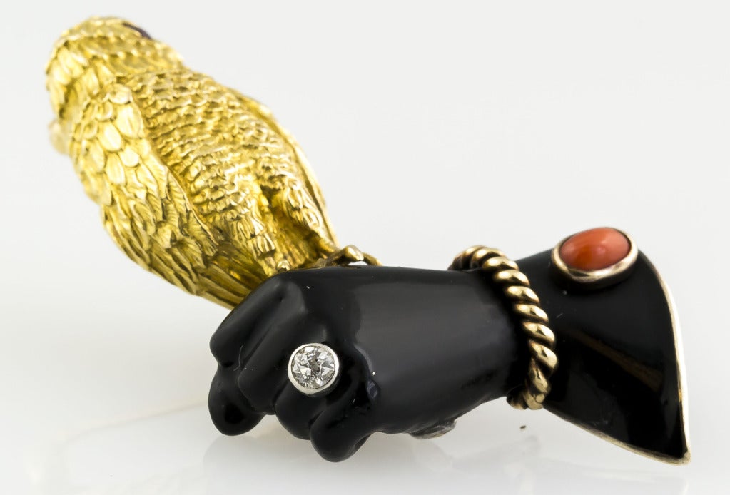 Beautiful and rare brooch depicting a falcon perched on a gloved hand, set with a coral cabochon, round diamond, and a round ruby.  With with black enamel and mounted in 18 k gold and silver.  Hallmarks: Cartier, Paris, reference numbers, maker's