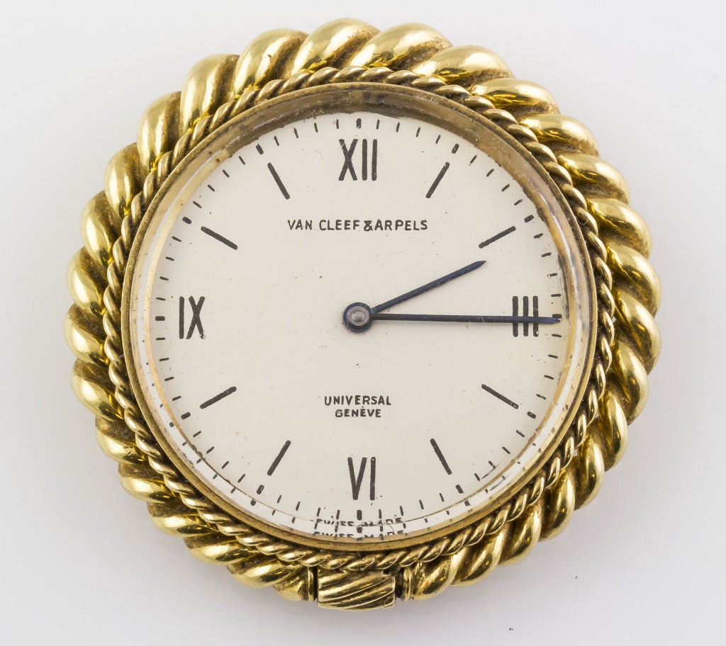 Van Cleef & Arpels chic 18k yellow gold travel clock. Twisted rope design for stand and crown. Features a mechanical movement by Universal. Charming clock is perfect for the bedside table or as an interesting travel piece.
 
Stamps: Van Cleef &