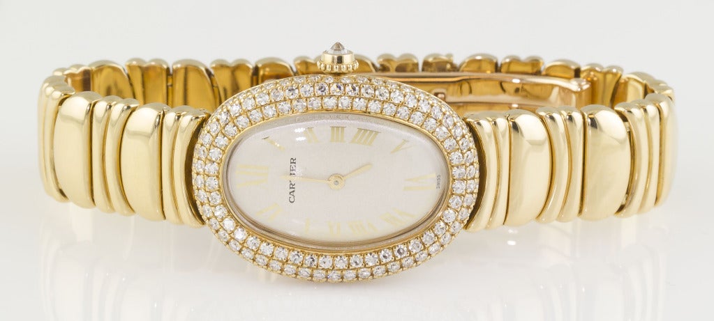 Elegant and feminine 18k yellow gold and diamond bracelet watch from the Cartier Baignoire collection. Featuring three rows of high-grade factory-original round cut diamonds and a quartz movement. Fully signed on case, dial and movement, as well as