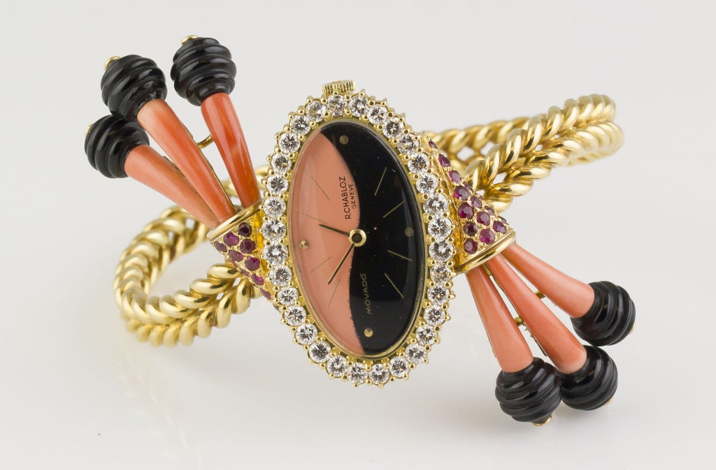Very rare and unusual 18K yellow gold, diamond, ruby, coral and onyx bracelet watch by Movado. It features very high grade round brilliant cut diamonds around the crown, along with rich red rubies at the top and bottom lugs. Also features coral