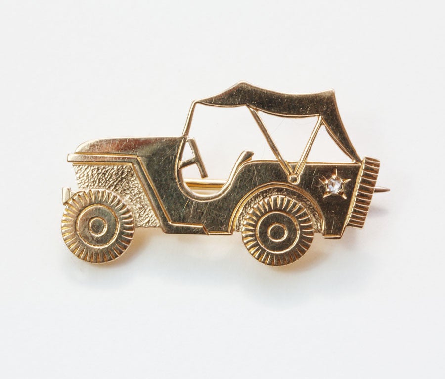 An 18 carat gold brooch in the shape of a jeep set with a small rose cut diamond, French master's mark, France, circa 1945, called a 