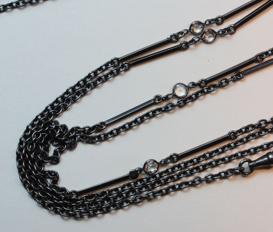 A long gun metal chain decorated with six brilliant cut pastes.

weight: 20.2 grams
length: 152 cm.