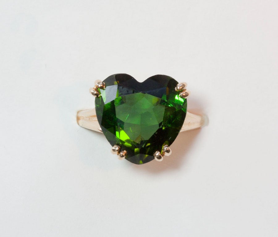 A 14 carat gold strong ring set with a heart shaped green tourmaline (circa 6,5 carats), signed and numbered: Tiffany & Co., V.S., 1947.

weight: 5.6 grams
ring maat: 16 mm. 5 1/4 US.