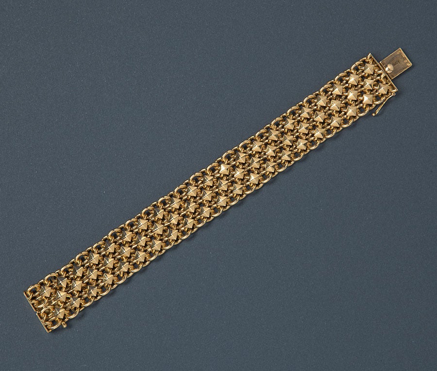 A braided 18 carat gold bracelet with konic gold decorations, signed and numbered: Cartier, Paris, 08057 (master's mark AC), circa 1950.

length: 18.5 cm.
width: 2.1 cm.