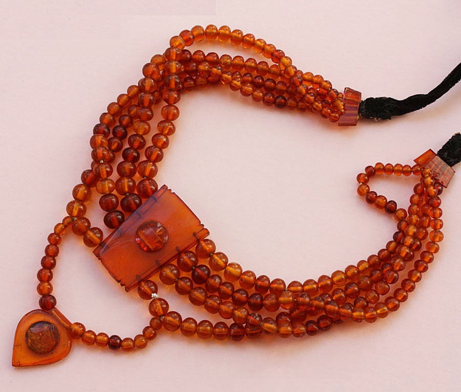 A necklace of four rows of amber - the length is adjustable with a velvet cord - decorated with two amber medallions.

Amber, once called the gold of the Baltic, is ancient fossilized resin that was primarly found floating in the Baltic Sea. In