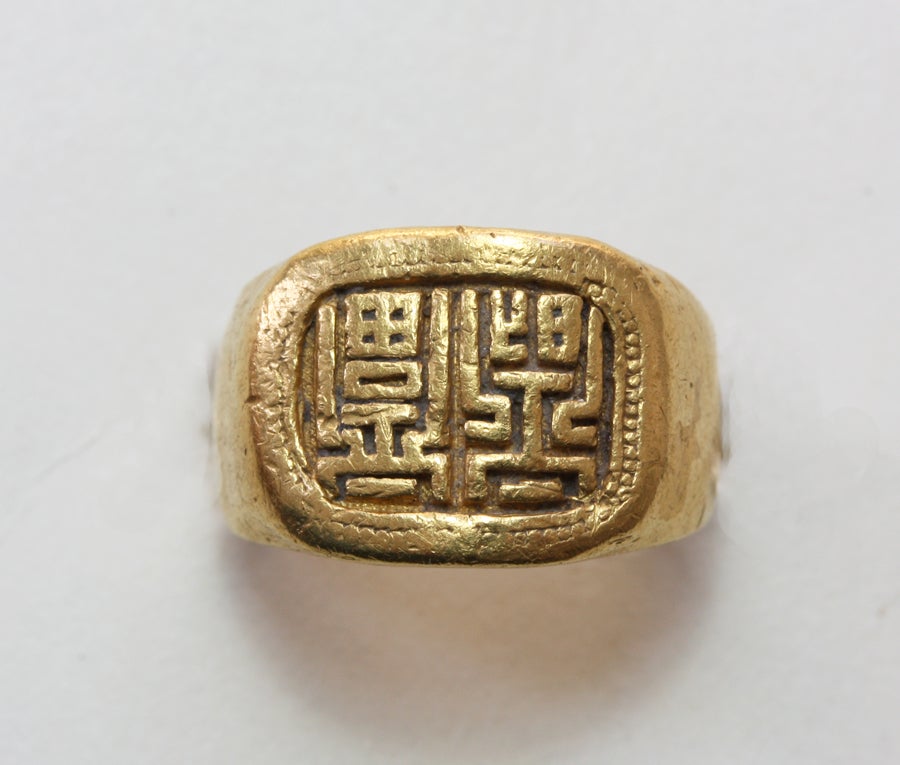 A small 24 carat gold ring with a seal with a message of happiness, translated as 