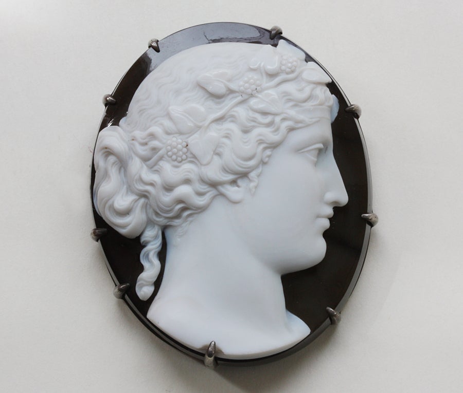A brooch with a beautiful large onyx cameo of a bacchante, a female devote of Bacchus (tiny chip), mounted in silver, 19th century, English or Italian.

weight: 59.2 grams
dimensions: 5.7 x 4.7 cm.