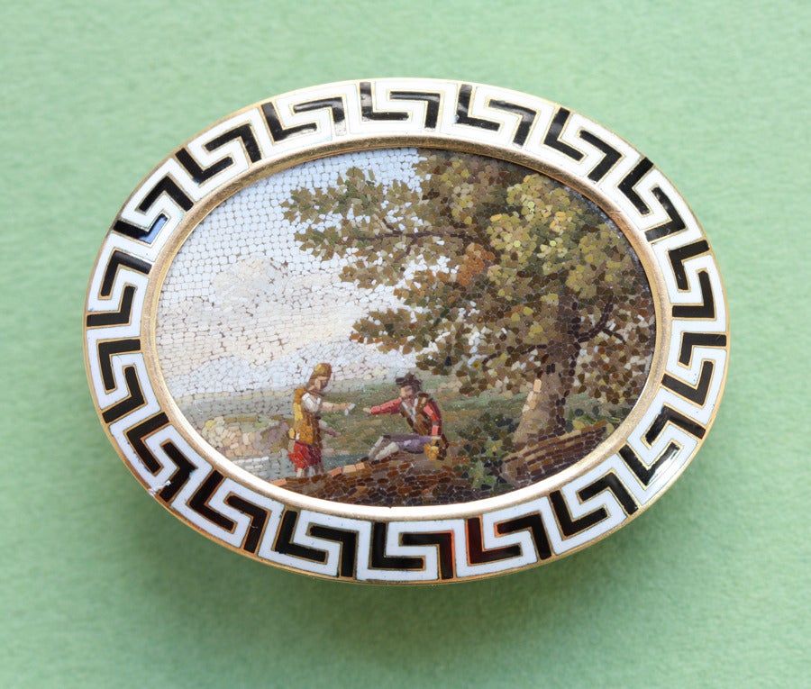 A very fine oval brooche with a micromosaic of a rural scene; two men reach towards each other, they shake hands or share a drink, Italy, 19th century, in a truly beautiful 18 carat gold mounting with a Greek meander border in black and white