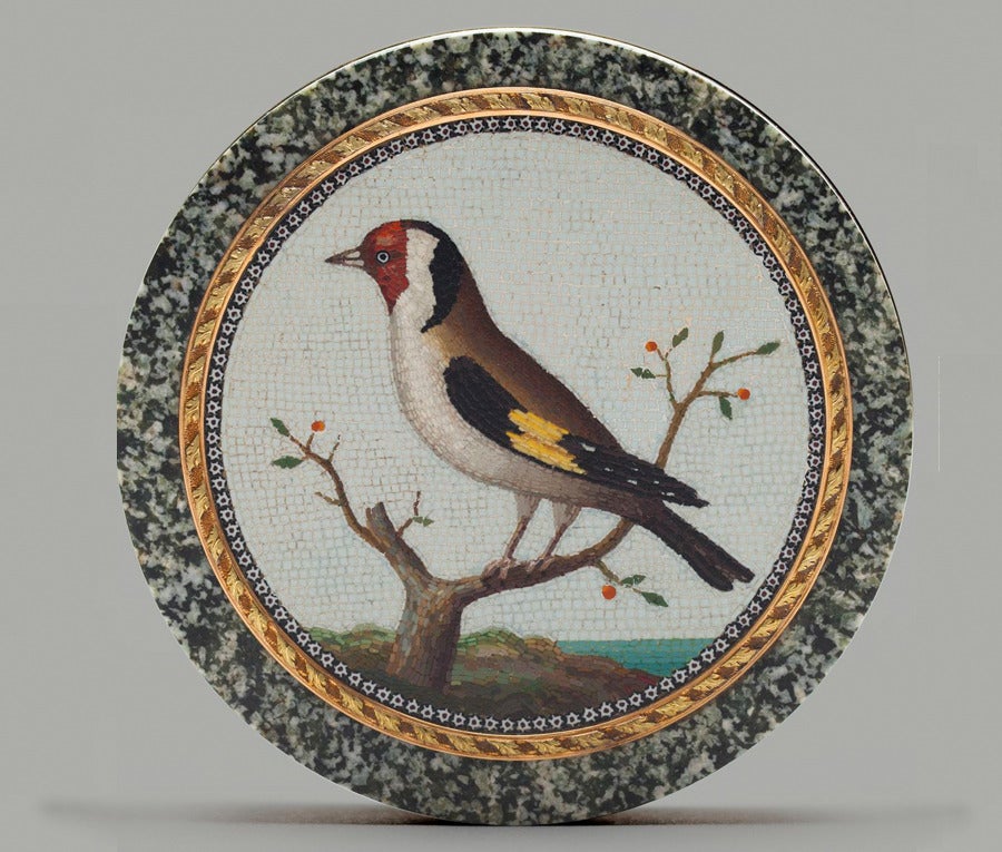 Boîte en granit vert italien, avec une micromosaïque montée dans une bordure ciselée en or bicolore. Un chardonneret (carduelis carduelis) est représenté sur une branche avec des baies, surplombant la Méditerranée. La scène est entourée d'une