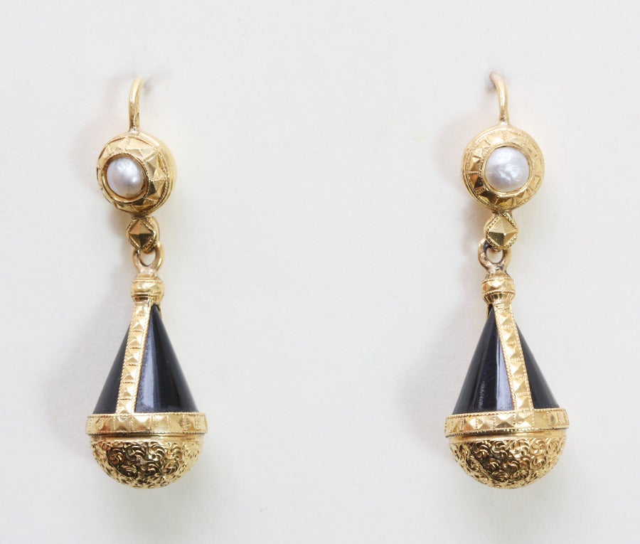 A pair 18 carat gold earrings with natural pearls and onyx drops all decorated with conically square elements the bottom with floral engravings, French gold and masters mark: LG, France, 19th century.

weight: 7.9 gram
dimensions: 4 x 1.7 cm.