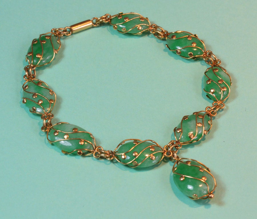 A bracelet of nine unpierced apple green jade stones in 20 carat gold cagework, China, circa 1910. 

Length: 20 cm.
Dimensions of each stone: 1.5 x 1 cm.