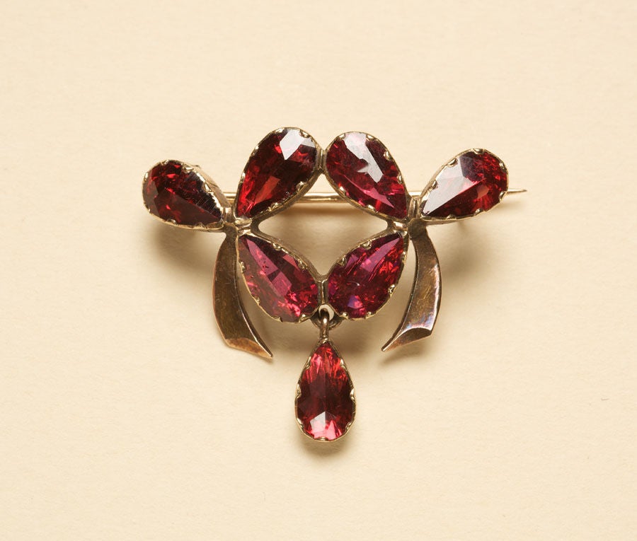 An 18 carat brooch set with foiled garnets, in the shape of clovers with a dangling drop, France, Perpignan, circa 1900.

weight: 4.7 gram
dimensions: 3.2 x 2.7 cm.