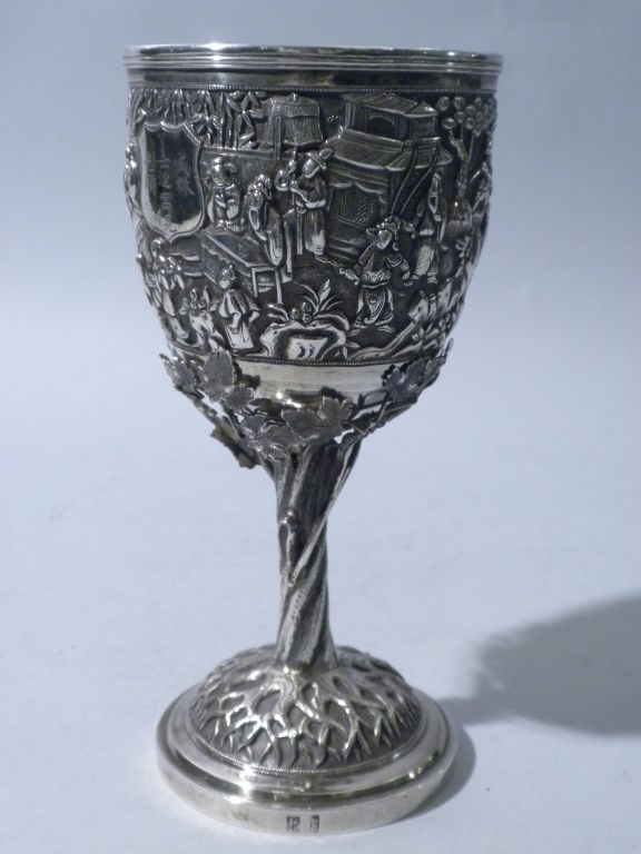 This substantial figural Antique Chinese Silver Goblet was made circa 1880. The underside of the base is hallmarked with Chinese characters. The cup is hand chased with a genre scene on a stippled ground, centering a monogrammed shield shaped