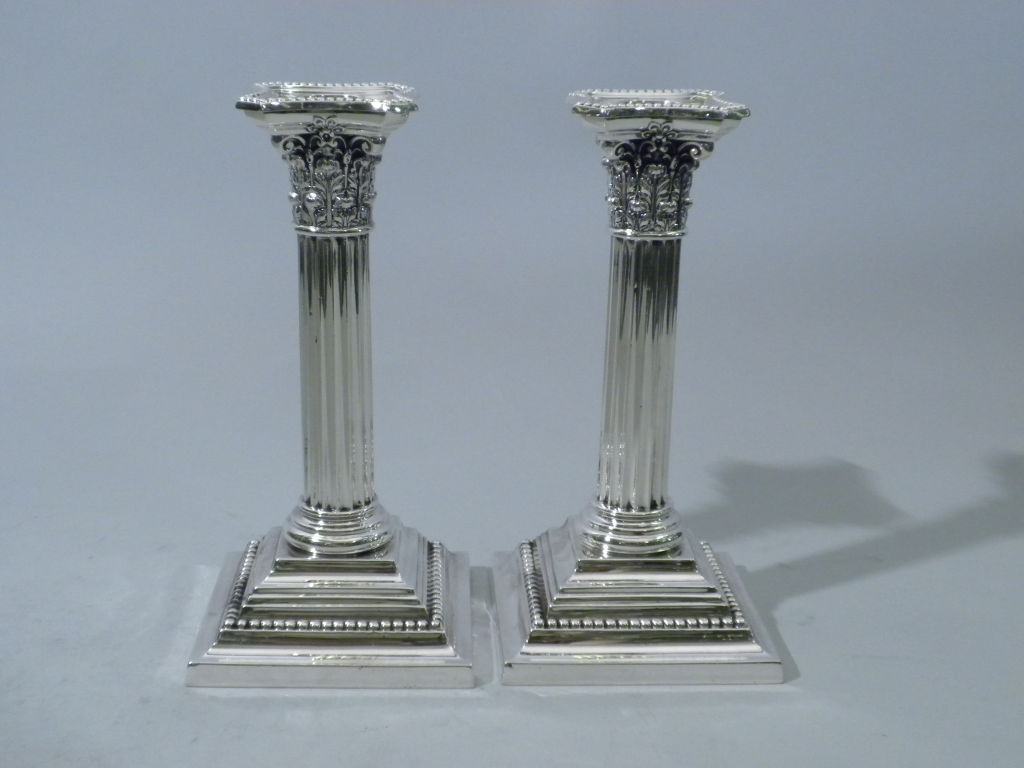 A pair of Antique American sterling silver candlesticks designed in the Corinthian Column style.  Beautiful Acanthus leaf scrollwork adorns the top of the ribbed column and heavy gauge beadwork is featured along the rim of each bobeche and at the