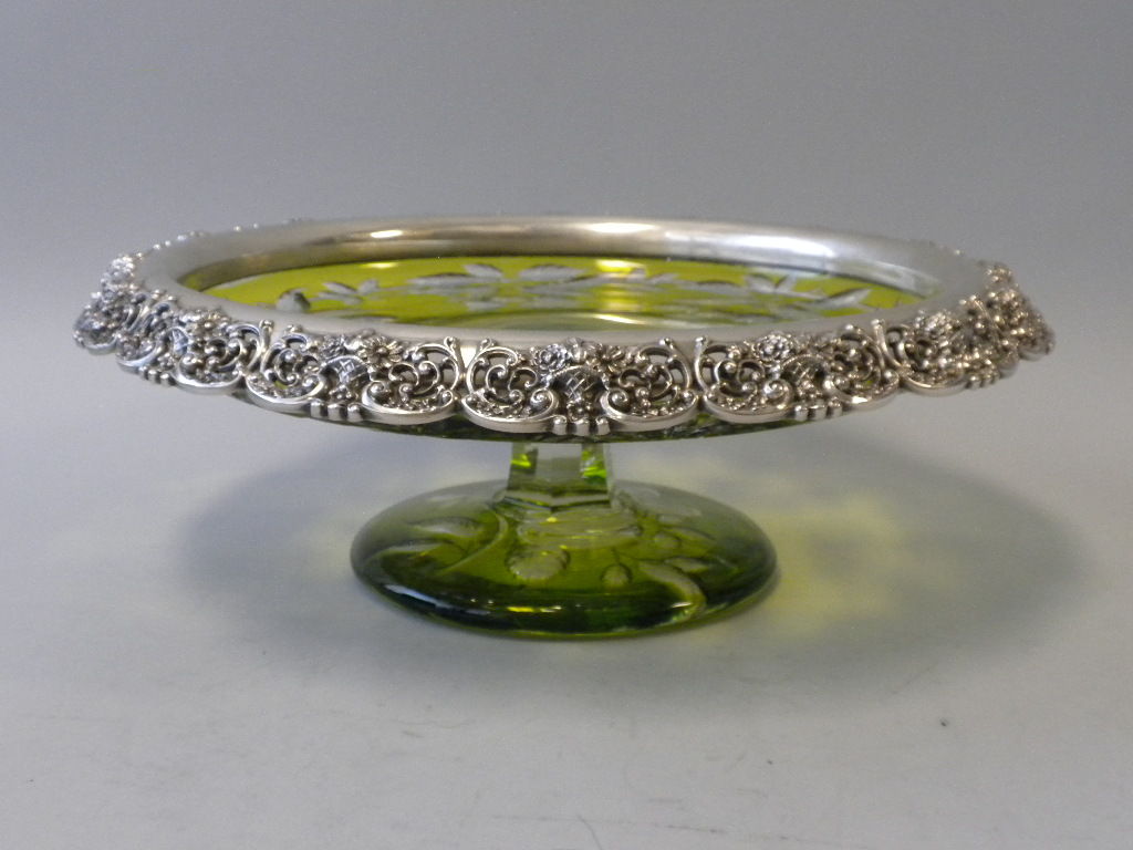 This is a prime example of the synergy of American silversmithing and American glassworks at its finest.  The footed cut crystal centerpiece is of lemon-lime ground with a clear wreath form cut decoration of clusters of cherries suspended from a