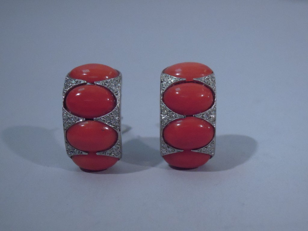Pair of modern earrings in diamond, platinum, and coral, ca. 1980. Each: Platinum arch with diamonds, and inset with coral ovals. A smart pair.
Excellent condition. Coral has a rich color.

Length: 1 in. Stock #1039