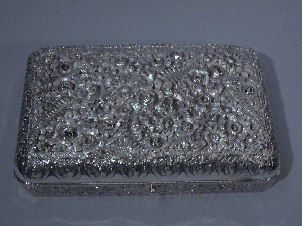 Sterling silver repoussé box. Made by Tiffany, ca. 1885. Rectangular with curved corners. Cover is hinged and curved, and has cabled rim. Allover repoussé flowers and foliage. Box and cover interior lightly gilt. The pattern (no. 8472) was first