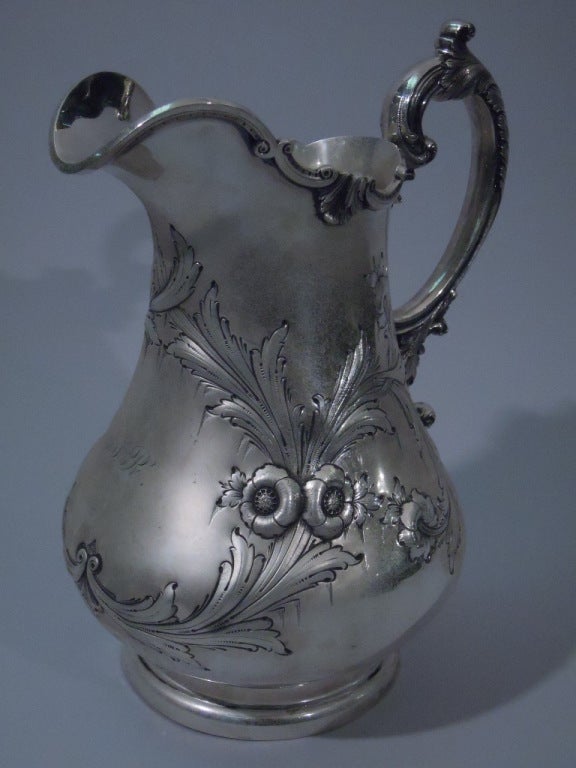 Coin silver water pitcher. Made in Philadelphia, ca. 1850. Retailed by Mitchell & Tyler in Richmond, Va. Baluster body, circular and stepped foot, wide lip spout, and foliate scroll handle. Repousse flowers and foliage on body. Asymmetrical and