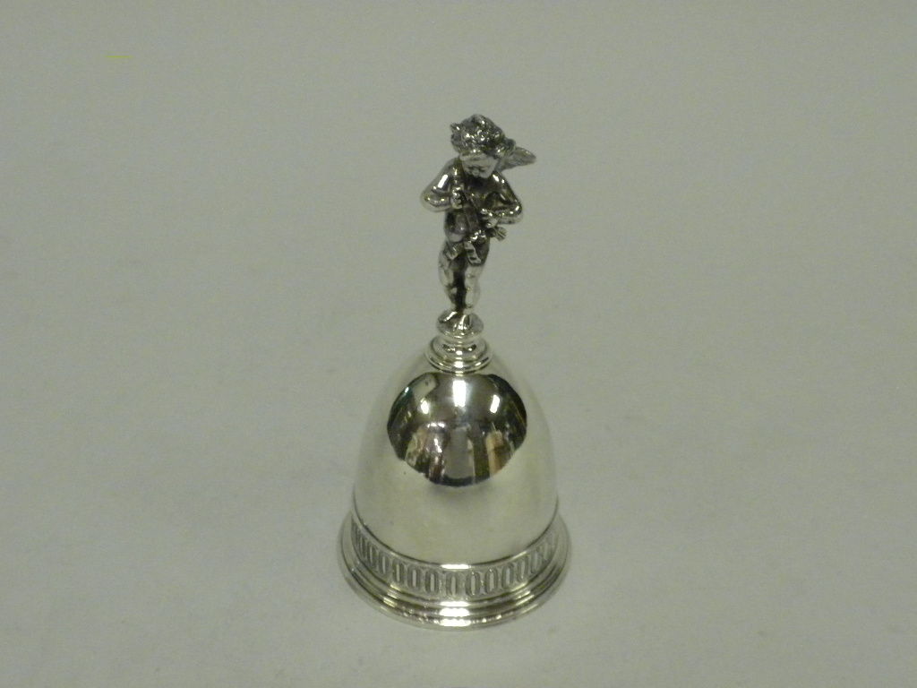 This is a rare sterling silver Table Bell with a putti or cherub handle, made by Tiffany & Co., New York, circa 1865.  The bell is elegantly designed and has a beautiful neoclassical applied egg and dart border at the molded base; the handle is