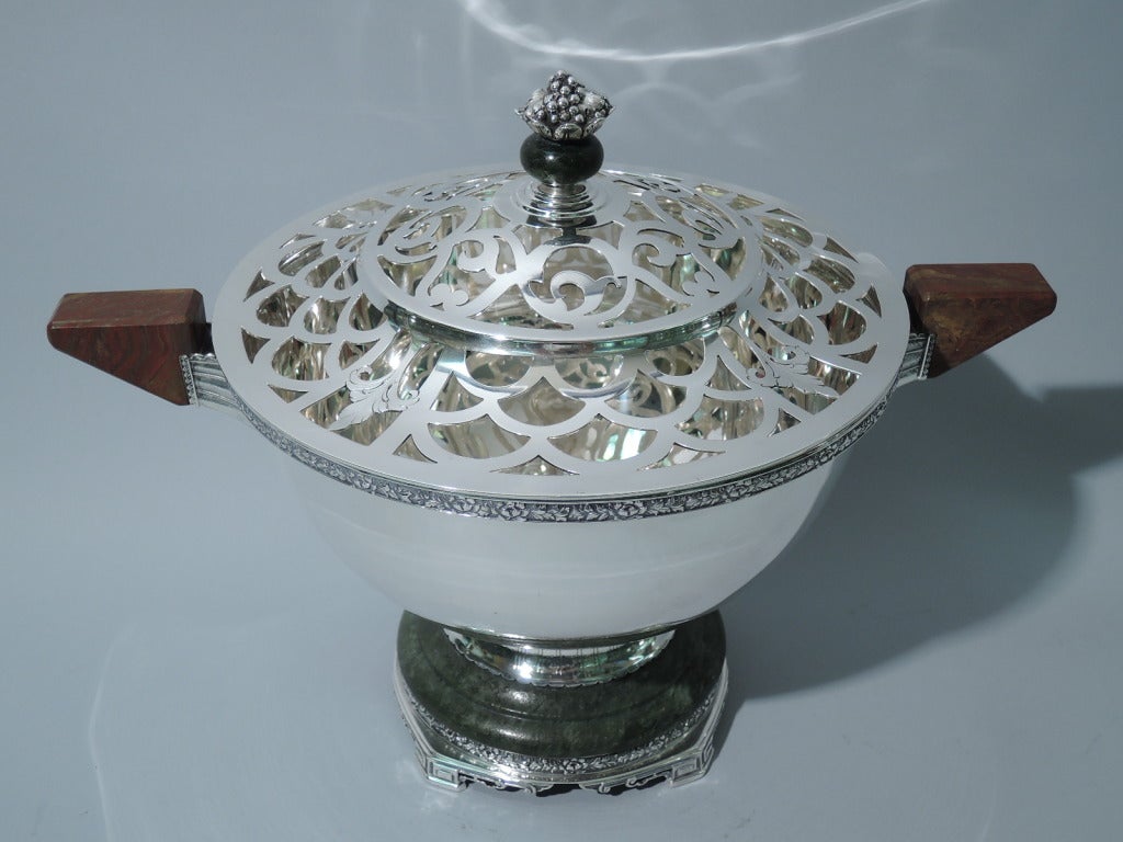 Art Deco garniture in sterling silver with hardstone mounts. Made by Lebkuecher in Newark, ca. 1920. This garniture comprises 2 candlesticks and 1 covered centerpiece bowl with flower arranger. 

Each candlestick: tapering shaft on stepped dome