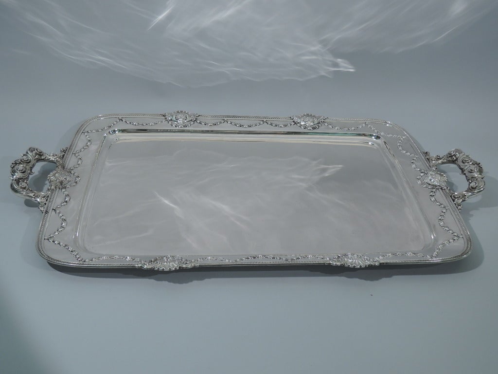 Sterling silver tea tray in Imperial Queen pattern. Made by Whiting in New York in 1909. Rectangular with curved corners and 2 side bracket handles. Plain well surrounded by applied garlands and shells. Handles comprised of scrolls and foliage.