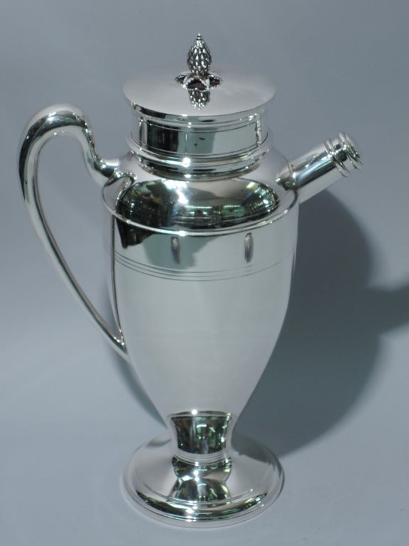 Sterling silver martini shaker. Made by Redlich in New York, ca. 1920. Ovoid body with scrolled handle and on raised foot. Cover is flat and snuggly fitted with bud finial. Spout is short and stubby with threaded cover. Hallmarked. Excellent